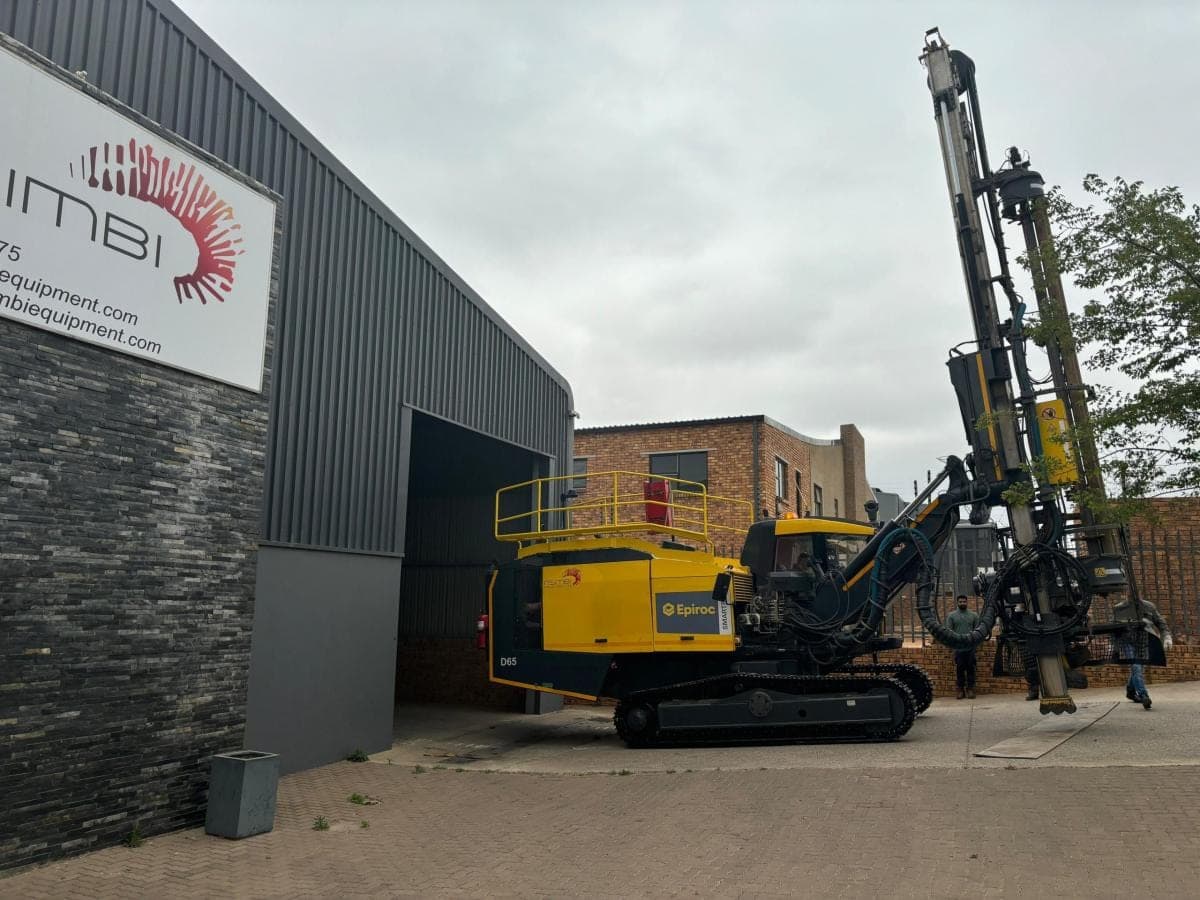 An Epiroc SmartROC D65 drill rig standing at the Nsimbi premises beside the company signage.