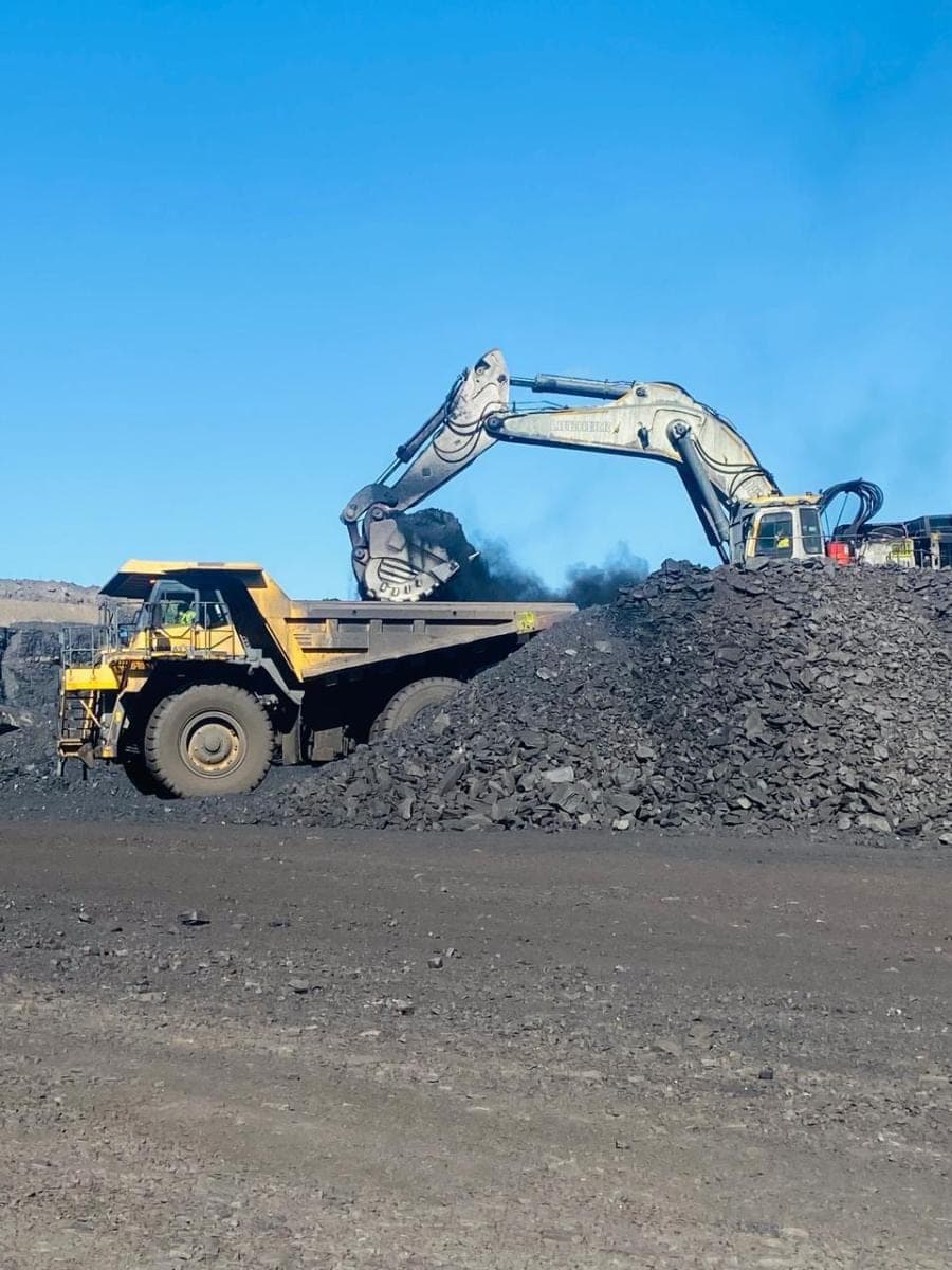 A Liebherr excavator tipping a bucket of coal into a waiting haul truck.