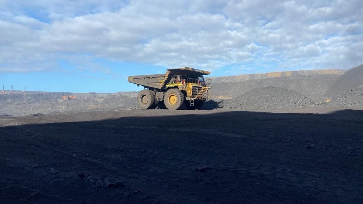 A Caterpillar haul truck crossing a coal bench under a broken sky.