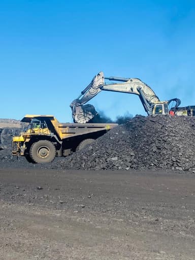 A Liebherr excavator tipping a bucket of coal into a waiting haul truck.
